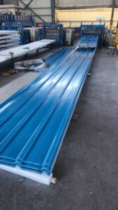 Blue PPGI corrugated sheets being produced in factory for building roofing - High-quality blue PPGI roof sheets from roll forming machine